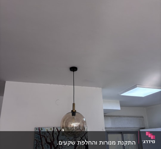 מנורה תלויה מהתקרה במטבח עם תמונה על הקיר